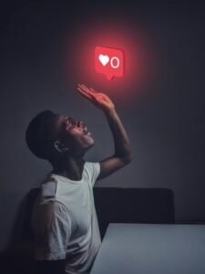 A man sits indoors reaching towards a glowing social media notification icon.